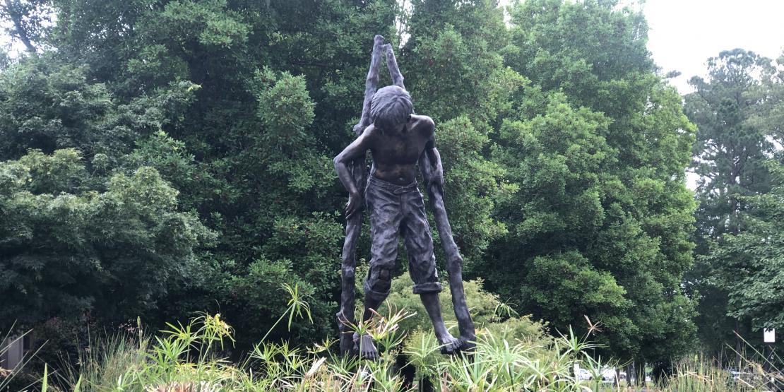 boy on stilts statue outside